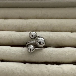 Trendig silverring med kulor - Cool ring i silverfärg med tre stora blanka kulor som ger en modern och unik look. Ringen har en öppen design där banden slingrar sig runt fingret och kulorna sitter i olika höjd. Perfekt för dig som gillar statement-smycken.