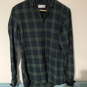 Grönrutig skjorta från Solid - Snygg grön och mörkblå rutig skjorta från Solid. Skjortan har klassisk krage, knäppning framtill och långa ärmar. Perfekt för dig som gillar en avslappnad men ändå stilren look. Tillverkad i mjuk bomull som känns skön mot huden. Öppen för bundles och frågor!  Man, kille, grisch, Stockholm, plagg, billigt, small, s, stil, stiligt, style, jacka, tröja, skjorta, kvalitet, märke, märkeskläder