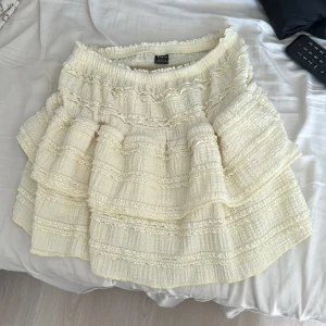 Volangkjol i gul från SHEIN  - Supersöt kort volangkjol från SHEIN i gul. Kjolen har flera lager med volanger och fina spetsdetaljer som ger en romantisk vibe. Perfekt för dig som gillar en feminin och trendig stil. Resår i midjan för skön passform.