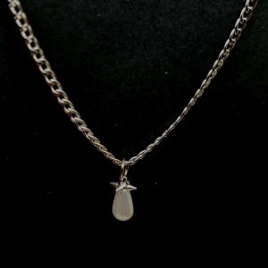 Silverhalsband med droppformad pärla - Stilrent halsband i silverfärg med en kedja och ett hängsmycke i form av en vit, droppformad pärla. Kedjan har klassisk länkdesign och pärlan sitter fast med en liten stjärnlik detalj upptill. Perfekt för dig som gillar minimalistiska smycken med en twist.