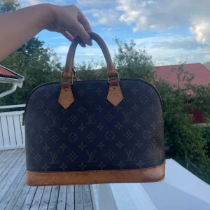 Louis Vuitton väska - Säljer nu min vintage Louis Vuitton väska Alma från år 2001! Det finns bevis på användning och därmed priset, som ni kan se på bilden har väskan en serienummer bevis på att den är äkta. Kan även tänka mig att byta mot en YSL loulou väska!🥰 Ps har fixat handtagaen  med läder tyg över då dem var slitna, ni ser allt på bild! 
