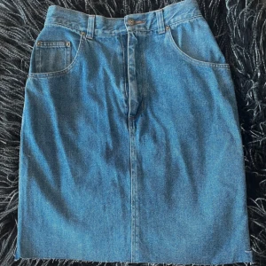 Snygg, rak jeanskjol med rå kant strl 36 från Lindex  - En snygg, rak jeanskjol i strl 36. Den är tillverkad för Lindex- Women’s Denim och har en rå kant utan söm längst ned. Lite mer stylish och kan användas vid de flesta tillfällen! Mått Midja 34 cm (68 cm runtom) L 50 cm  Bredd över stuss 45 cm