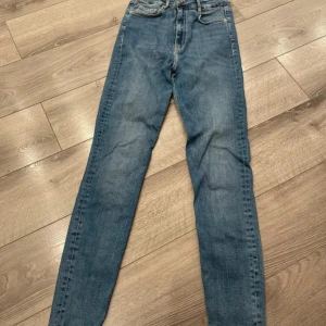 Blå skinny jeans med hög midja - Snygga blå skinny jeans med hög midja och klassisk femficksdesign. Jeansen har en smal passform och är tillverkade i mjukt denimtyg med lite stretch för extra komfort. Perfekta till sneakers eller boots.