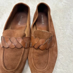 Bruna mockaloafers från Anna Field 38 - Snygga loafers i brun mocka från Anna Field med flätad detalj i läder över foten. Skorna har en klassisk, rund tå och platt sula, perfekta för en stilren vardagslook.