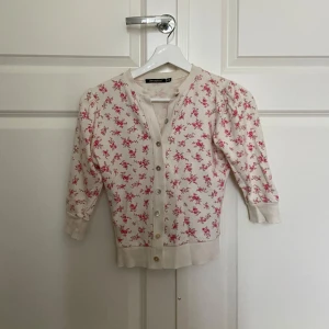 Blommig söt kofta! - Supersöt kofta med rosa blommigt mönster som jag hittat secondhand. Koftan har trekvartsärmar, rund hals och knappar framtill som ger en liten unik look. Perfekt för dig som behöver något nu inför att sommar bli höst❤️