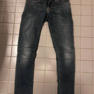 Mörkblå skinny jeans - Snygga mörkblå jeans med skinny fit och klassisk femficksdesign. Jeansen har lätt slitna detaljer på låren och knäna för en cool look. Perfekta till sneakers eller boots och passar till det mesta i garderoben.