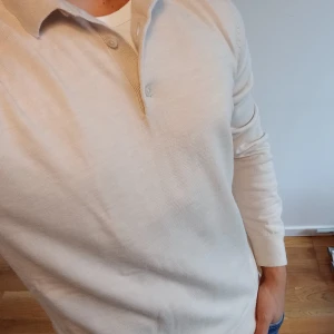 Beige stickad pikétröja i merinoull, Pris går att diskuteras - Säljer en beige stickad pikétröja från Dressmann i storlek M (passar alla som bär S-L). Tröjan har klassisk krage, tre knappar vid halsen och är knappt använd. Materialet är mjuk merinoull, perfekt varm för de kallare årstiderna och dig som vill vara stilren. Pris går självklart att diskuteras!