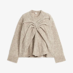 Beige stickad tröja med knytdetalj - Säljer en beige stickad tröja från Arket med rosett knytning framtill. Aldrig använd.