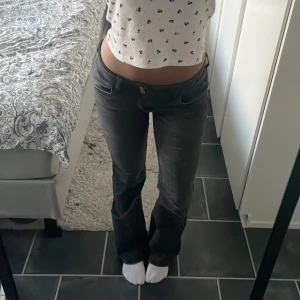 Svarta bootcut jeans - Säljer ett par svarta jeans med bootcut-modell och låg midja. Jeansen har klassisk femficksdesign och är tillverkade i ett stretchigt denimtyg som sitter snyggt över höfterna och låren. Perfekta för dig som gillar en retro vibe och vill ha en cool siluett.