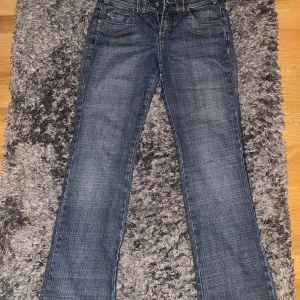 Vintage blå bootcut  jeans   - Snygga blå jeans från Trussardi Jeans med klassisk bootcut-modell. Jeansen har fem fickor, kontrastsömmar och en läderpatch bak i midjan. Tillverkade i slitstarkt denim med en cool tvättad look. Perfekta för dig som gillar en tidlös och avslappnad stil.