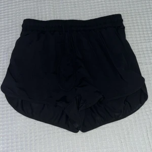 Svarta badshorts från Firefly XS - Svarta badshorts från Firefly i storlek XS. De har elastisk midja och är tillverkade i ett snabbtorkande material med 84% polyamid och 16% elastan. Perfekta för stranden eller poolen, med klassisk sportig look och bekväm passform.