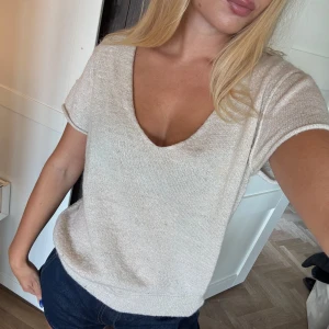 Glittrig beige stickad topp med v-ringning - Superfin beige stickad topp med diskret guldglittriga trådar och v-ringning. Kortärmad och perfekt nu till hösten eller sensommarkvällar 🥰