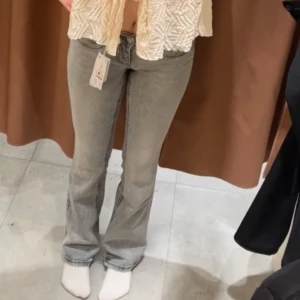 Grå bootcut jeans med låg midja - Snygga grå jeans med bootcut passform och låg midja. Snygga detlaj på bakfickorna. Använda någon enstaka gång, små skavanker längst ner då det varit lite för långa på mig.