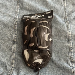 Svarta skyddshandskar från Stiga - Skydd för armbåge,händer och knän från Stiga i svart med ljus gråa detaljer, perfekta för sport och träning. De kommer i ett praktiskt nätfodral. Snygg och sportig design som ger bra grepp och skydd.