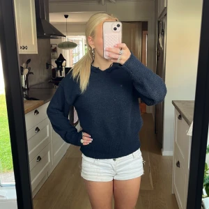 Mörkblå stickad hoodie med huva - Mysig mörkblå stickad hoodie med huva och snörning. Tröjan har långärmade ärmar och en loose passform som ger en chill vibe. Perfekt för dig som gillar enkel stil med lite extra komfort. Passar till jeans eller shorts för en avslappnad look. Storlek 152
