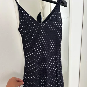 Svart prickig kortklänning H&M XS - Supersöt svart kortklänning från H&M med vita prickar och smala justerbara axelband. Klänningen har en v-ringad hals och ärmlös design, perfekt för varma dagar. Mjuk och skön bomullskvalitet som sitter snyggt och bekvämt. Enkel att matcha med sneakers eller sandaler. Pris går att diskutera såklart🖤🤍💙