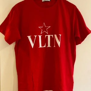 Röd VLTN t-shirt från Valentino - Snygg röd t-shirt från Valentino med VLTN-tryck och en vit stjärna på bröstet. Klassisk rund hals och korta ärmar. Tillverkad i mjuk bomull, perfekt för dig som gillar exklusiva märken och stilren design.