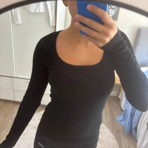 Svart ribbad långärmad topp - Säljer en likadan i vit!!                                           Svart långärmad topp med ribbad struktur och rund, djup urringning. Sitter tight och har en enkel, stilren look som funkar till allt. Gjord i mjukt bomullsmaterial som är skönt mot huden.