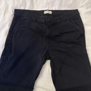 Svarta chinos från Esprit - Snygga svarta chinos från Esprit med klassisk rak passform. Byxorna har sidfickor, bälteshällor och en bakficka med knapp. Perfekta för en clean och stilren look. Tillverkade i mjuk bomull för skön känsla hela dagen.