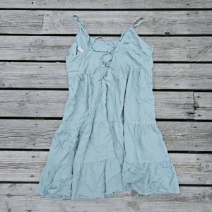Volangklänning - En riktigt fin och unik volangklänning i underbar pastellton – mix mellan turkos, mintgrön, babyblå och ljusgrön. Kortare modell med vackert fall och justerbar knytning i ryggen som gör att den sitter snyggt på flera storlekar. Orginalt en storlek M