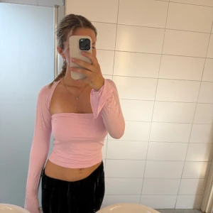 Rosa tröja  - Säljer en rosa tröja från Ginatricot, sitter som en bandå topp men med ärmar. Har även slits i ärmarna. 