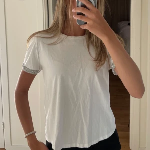 Vit T-shirt med glittriga detaljer - Vit t-shirt med glittriga detaljer på ärmarna. Från zara. Använd men i fint skick. Strl S