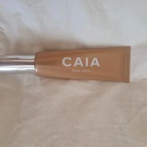 CAIA Pearl Swirl Liquid Highlighter - Flytande highlighter från CAIA i nyansen Pearl Swirl. Kommer i en snygg beige tub med silvrig kork. Perfekt för att ge huden en glowig och fräsch finish. Enkel att applicera och smälter fint in i huden.