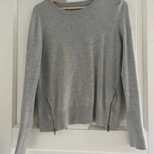 Grå stickad tröja med dragkedjor  - Snygg grå stickad tröja från InWear i storlek S. Tröjan har rund hals, långa ärmar och dragkedjor på sidorna vid nederkanten. Perfekt för hösten💞