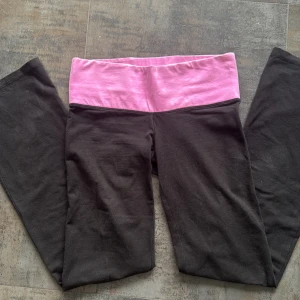 Svarta yoga leggings från Victoria's Secret PINK - Svarta flared leggings från Victoria's Secret PINK med bred rosa midja och stor PINK-logga bak. Supersköna och stretchiga, perfekta för yoga eller chill. Materialet är mjuk bomullsblandning och midjan är låg vilket är perfekt för er som gillar Y2K/ Stockholm stil. Har ett litet hål på rumpan men det märks inte.