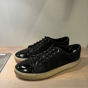 Lanvin cap toe - Säljer ett par Lanvin cap toe-skor i gott bruksskick, med en del kvar att ge. Skorna har en del spår av användning - bland annat lagningar på hälen, mockan är i sämre skick och nägra repor i lacken (se bilder för alla defekter) kontakta gärna vid frågor