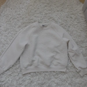 Beige quiltad sweatshirt från Weekday - Säljer en beige sweatshirt från Weekday i storlek small. Tröjan har quiltad struktur på både fram- och baksida, släta ärmar och ribbade muddar. Det syns att tröjan är använd och har små fläckar vid ärmar. 