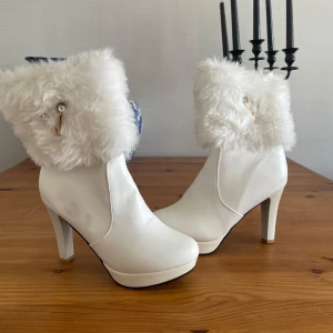Vita boots med fuskpäls och klack - Säljer dessa fina vinterboots. Skorna är i fint skick men de förekommer lite märken på ena skon. Se bilder. Vet ej märket så jag säljer dem ganska billigt. Passar mig bra som har 41 men tyvärr använder jag aldrig högklackat så därför säljer jag nu dem💕