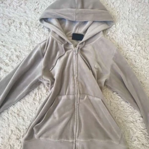 Beige velour hoodie Juicy Couture XS - Säljer en beige hoodie från Juicy Couture i mjuk velour med dragkedja och huva. Tröjan har långa ärmar, snörning vid halsen och broderad JC-logga på bröstet. Perfekt för chill dagar och har klassisk Juicy Couture-vibe.