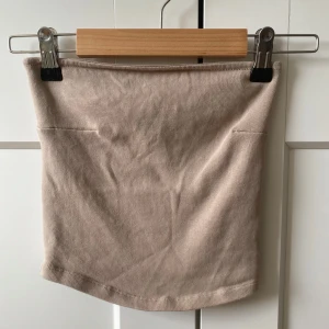 Beige ribbad stretch tube top från Gina Tricot - Supersnygg beige ribbad stretch tube topp från Gina Tricot i mjuk stretchig bomull. Toppen har en enkel och clean design med tight passform, perfekt att matcha med en kjol eller jeans . Färgen är neutral och funkar till allt.