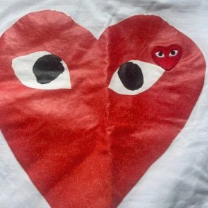 Vit Comme des Garçons Play t-shirt - Vit t-shirt från Comme des Garçons Play med det ikoniska röda hjärtat med ögon tryckt på bröstet. Klassisk rund hals och korta ärmar. 