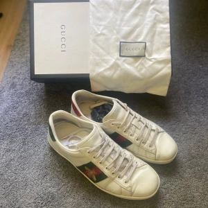 Gucci ace bee sneakers | Storlek 43,5 - Säljer ett par klassiska Gucci Ace Bee sneakers. ✅Äkta vara – kommer med originalkartong, dust bag och autenticitetskort (se bilder) ✅Bekväma och stilrena – passar både till vardags och lite mer uppklätt ✅Använda men i helt okej skick – se bilder för egen bedömning. Notering : Fläck på dustbag. ‼️Pris kan diskuteras vid snabb affär‼️