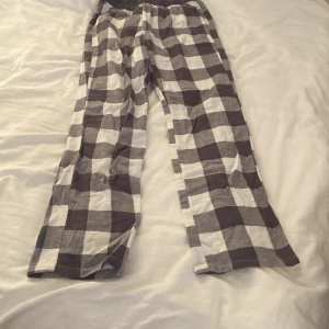 Rutiga mjukisbyxor från Kappahl - Superbekväma mjukisbyxor från Kappahl i storlek 146/152. Byxorna har ett rutigt mönster i grått och vitt samt bred resår i midjan med texten 'UNIQUE GRL'. Perfekta för chill dagar hemma eller som pyjamasbyxor.