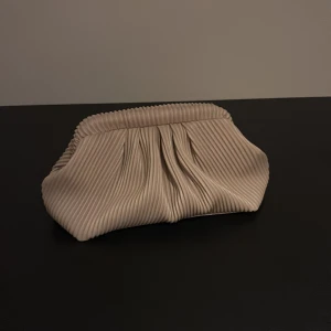 Beige clutch väska  - Snygg beige kuvertväska. Insidan är svart och har plats för det viktigaste. Perfekt att bära i handen. Säljer då jag aldrig använt den