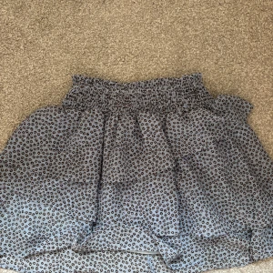 Blå leopardmönstrad kjol H&M - Supersöt blå kortkjol från H&M med leopardmönster och volangdetaljer. Kjolen har en smockad midja som sitter skönt och ger en snygg passform. Perfekt för dig som vill sticka ut lite extra med ett trendigt djurmönster.