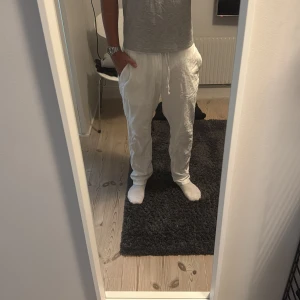 Vita linnebyxor med snörning - Säljer ett par vita linnebyxor med avslappnad passform och elastisk midja med snörning. Perfekta för varma dagar och chill vibes. Byxorna har raka ben och är tillverkade i svalt linne för extra komfort.