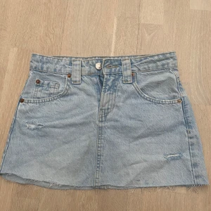 Ljusblå jeanskjol från Stradivarius - Ljusblå jeanskjol från Stradivarius med rå kant nertill och slitna detaljer framtill. Perfekt för skolstarten. Rätt så liten i storleken, aldrig använd 💗