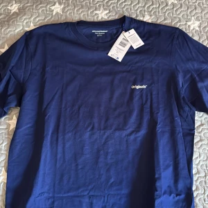 Blå oversized t-shirt Jack & Jones - Snygg oversized t-shirt från Jack & Jones Originals i marinblå färg. Framsidan har en liten vit Originals-logga och baksidan har ett stort tryck med texten 'Le Ponton Montpellier' och en brun botanisk illustration. Mjuk bomullskvalitet och klassisk rund hals.