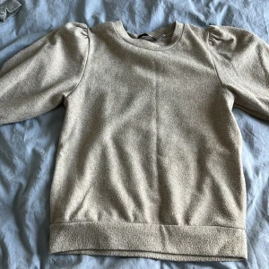 Beige långärmad tröja från 157 XS - Säljer en beige långärmad tröja från 157 i storlek XS. Tröjan har puffade axlar och en rund halsringning. Materialet är mjukt och känns som bomull, perfekt för dig som gillar enkel och chill stil. Passformen är normal och muddar finns vid ärmslut och nederkant.