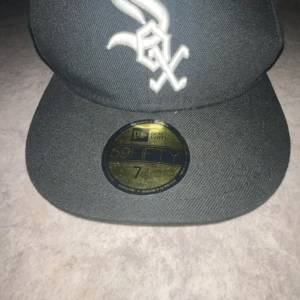Svart New Era 59FIFTY keps White Sox - Snygg svart keps från New Era, modell 59FIFTY med White Sox-logga broderad i vitt framtill och New Era-logga på sidan. Platt skärm och klassisk passform. Perfekt för dig som gillar streetwear och sportiga vibes.
