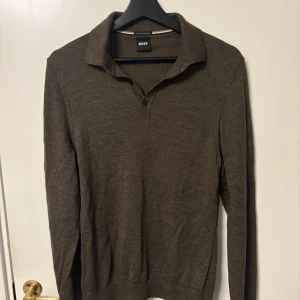 Brun pikétröja från BOSS - Snygg brun pikétröja från BOSS med klassisk krage och två knappar vid halsen. Perfekt för dig som gillar stilrena och enkla plagg med en touch av premiumkänsla. Aldrig använd bara testad. Str S ganska kort tröja så passar nog dig som är runt 175 cm lång