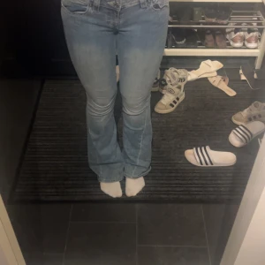 Ljusblå bootcut jeans med fickdetaljer - Säljer ett par ljusblå bootcut jeans med snygga fickdetaljer bak och klassisk femficksdesign. Jeansen har låg midja och är tillverkade i mjukt denimtyg. Perfekta för dig som gillar en retro vibe och vill ha ett par jeans som sticker ut lite extra.
