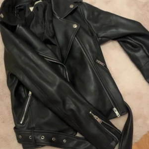 Svart skinnjacka med dragkedjor - Snygg svart skinnjacka med coola silverfärgade dragkedjor och detaljer. Perfekt till fest och även till vardags,säljer pga att den blivit för liten. Köpt från Nelly nypris 500kr. Jackan är i fint skick utan synliga defekter🥰