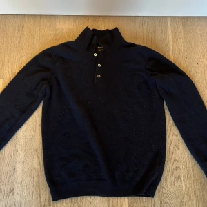 Mörkblå tröja från Massimo Dutti - Snygg mörkblå kashmir tröja från Massimo Dutti med knappar framtill. Perfekt för en stilren look. Tröjan har långa ärmar och en klassisk krage. Tröjan är i nyskick