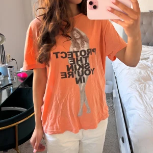 Orange t-shirt från Marc Jacobs - Säljer en cool orange t-shirt från Marc Jacobs med texten 'PROTECT THE SKIN YOU'RE IN' extremt svår att få tag i