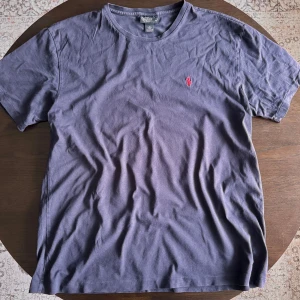 Mörk blå Ralph Lauren T-shirt  - Här är en mörkblå Ralph Lauren t-shirt med en klassisk röd logga. Väldigt bra skick och har mestadels hängt i garderoben. Det är storlek medium och passar bra till nästan allt. Speciellt nu när det börjar bli lite varmare ute.